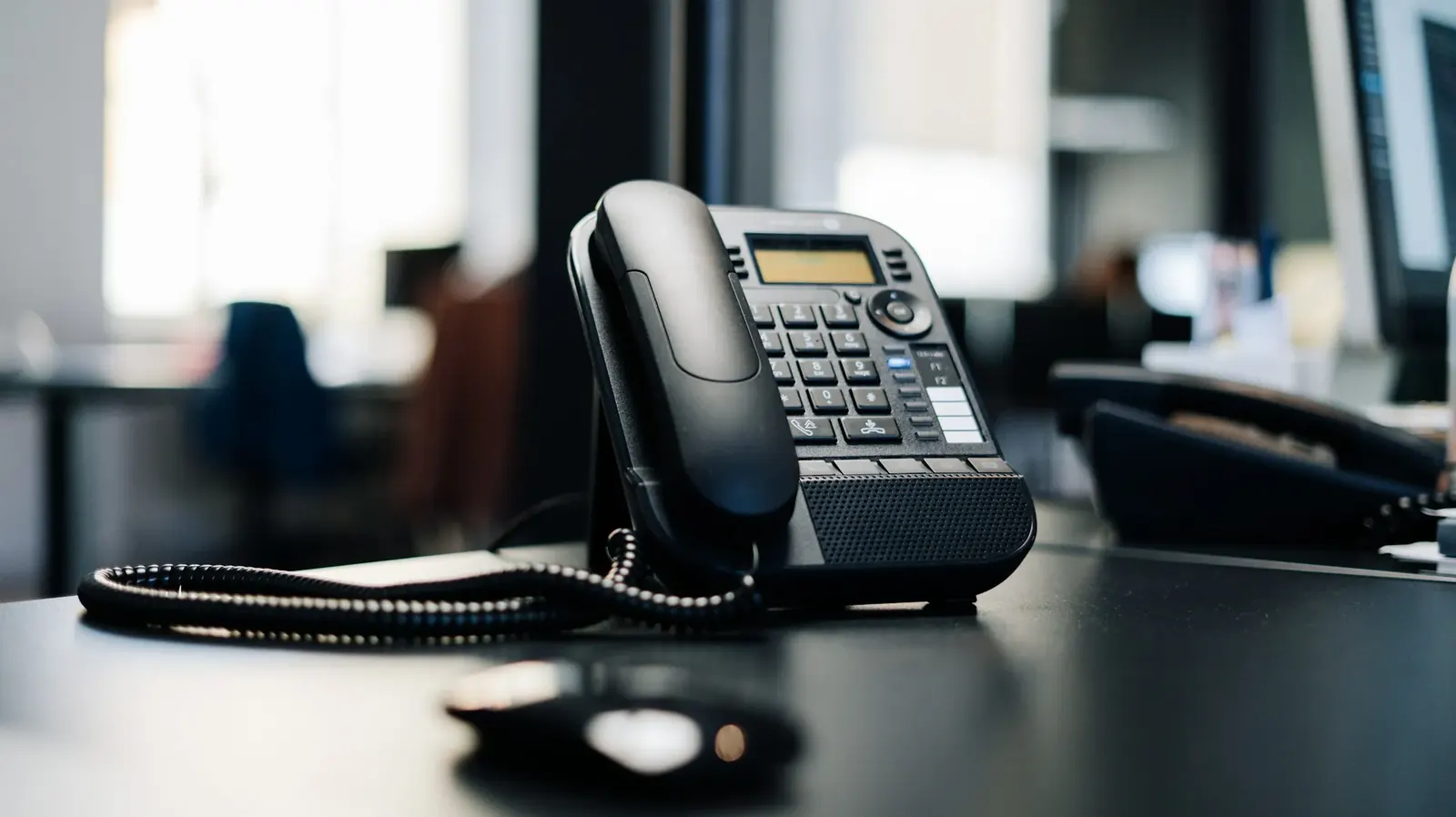 Office desk telephone beside a notepad