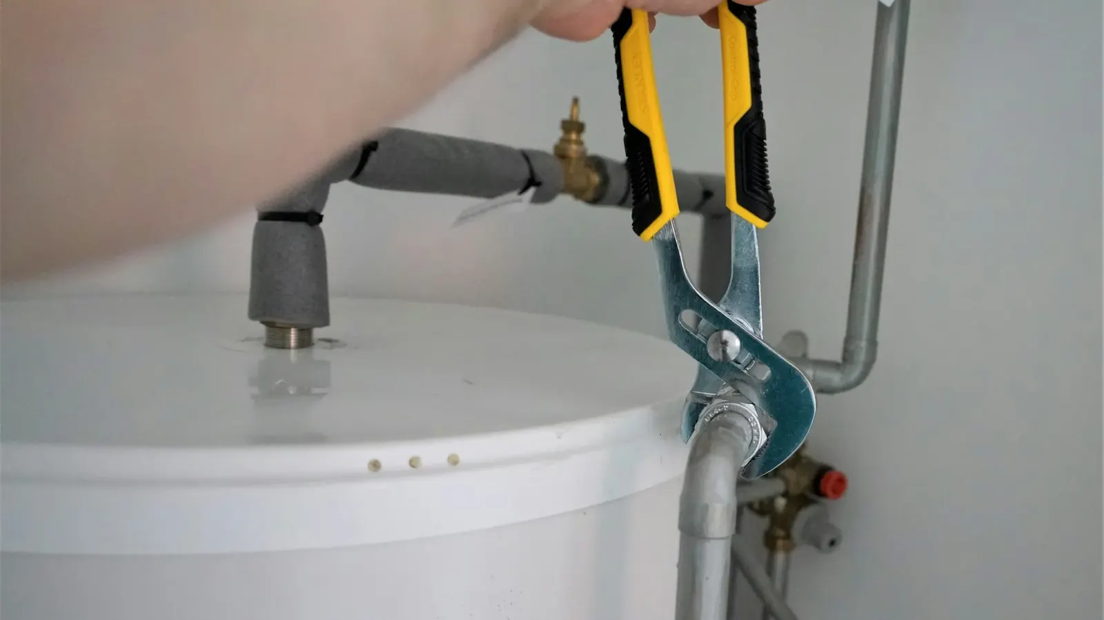 Technician working on a water heater with a wrench