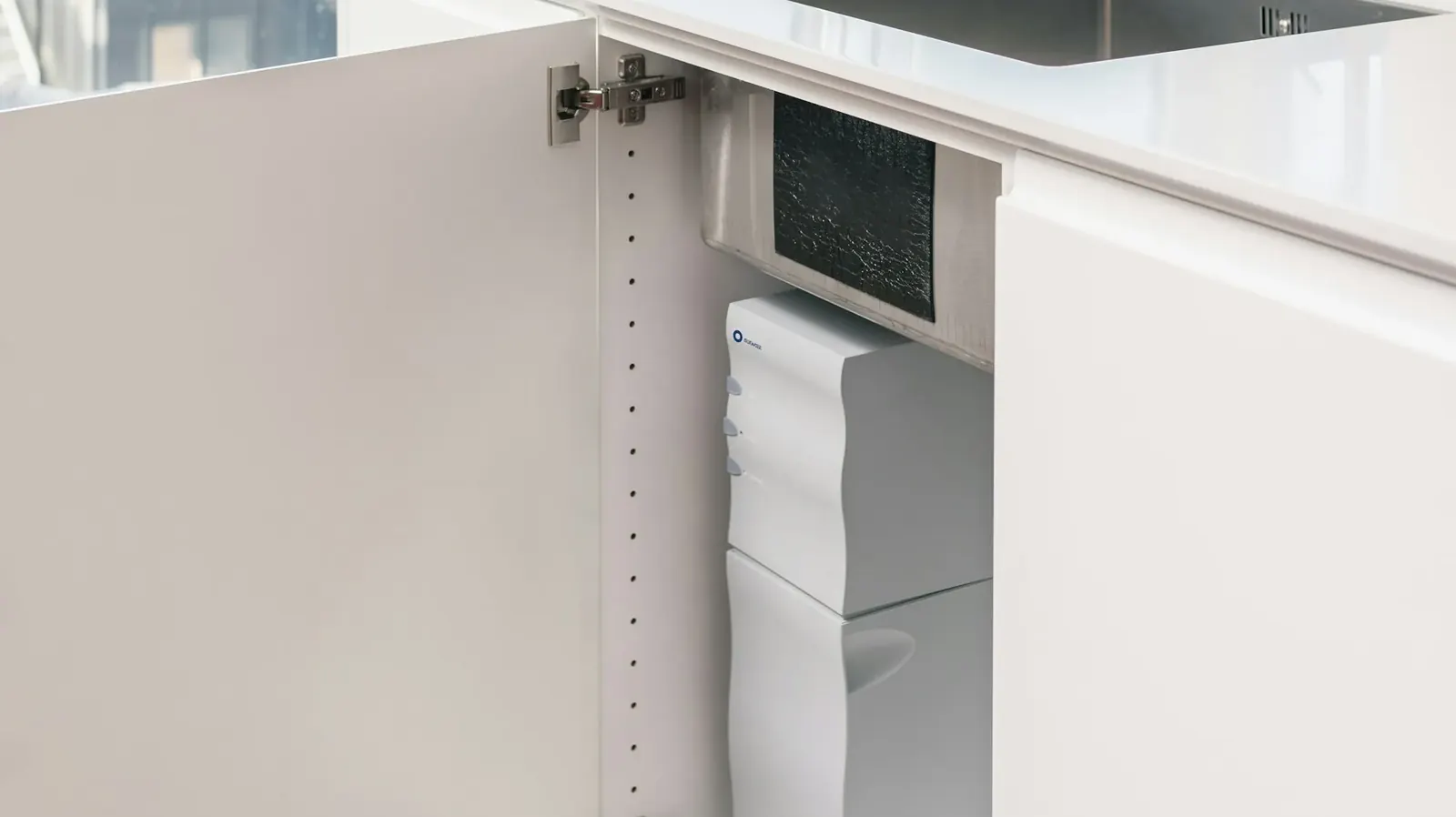 Open kitchen cabinet showing a compact filter